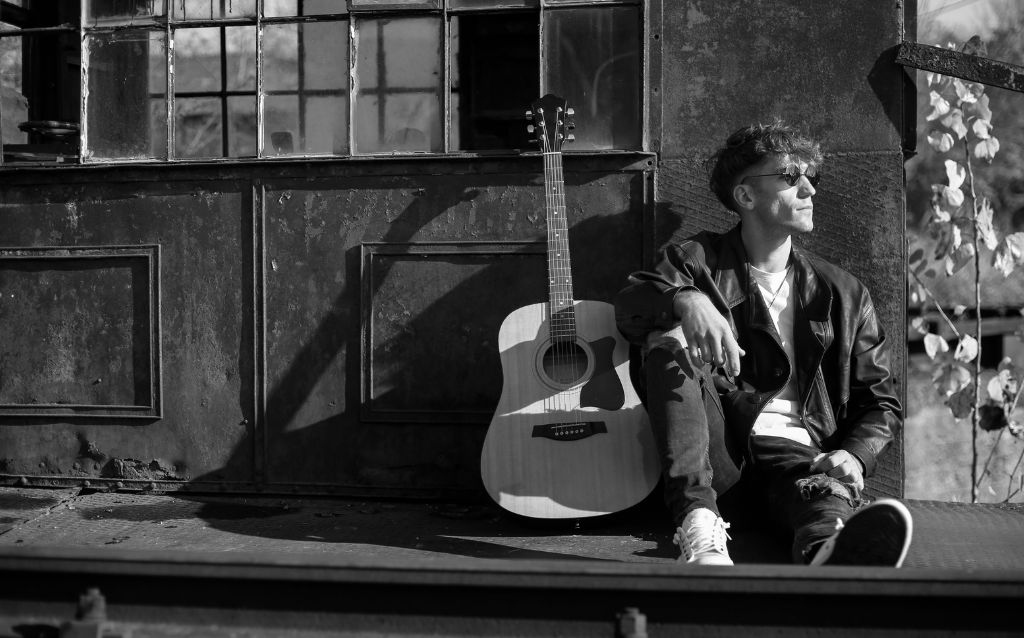 Man sitting on porch with acoustic blues guitar